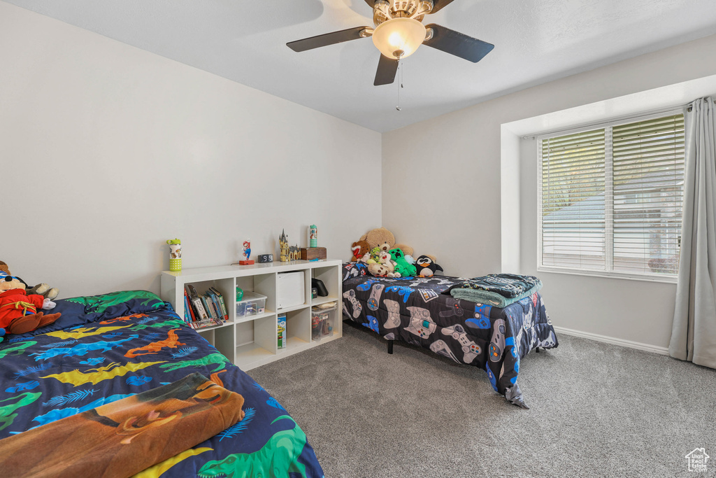 Carpeted bedroom with a ceiling fan and baseboards