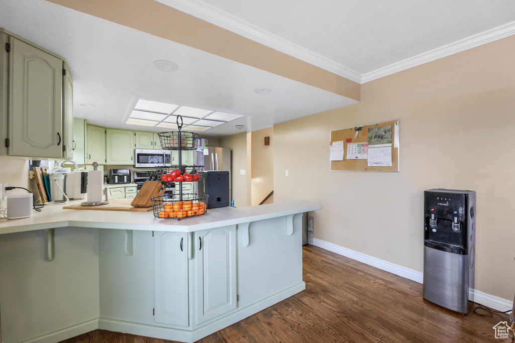 Kitchen with light countertops, a peninsula, stainless steel microwave, and baseboards