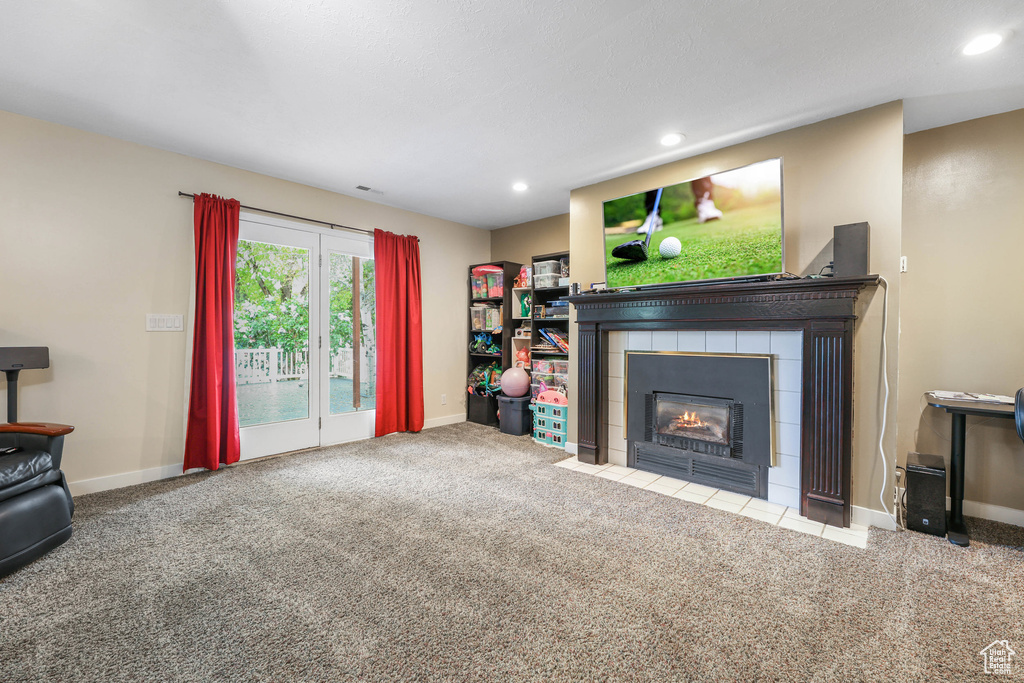 Carpeted living room with recessed lighting, baseboards, visible vents, and a tile fireplace