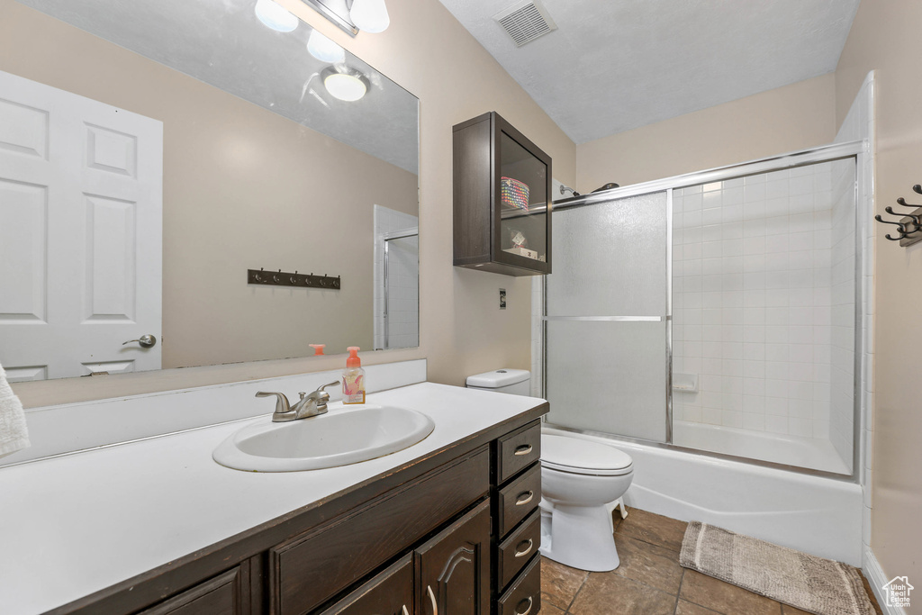 Full bath featuring visible vents, shower / bath combination with glass door, toilet, and vanity