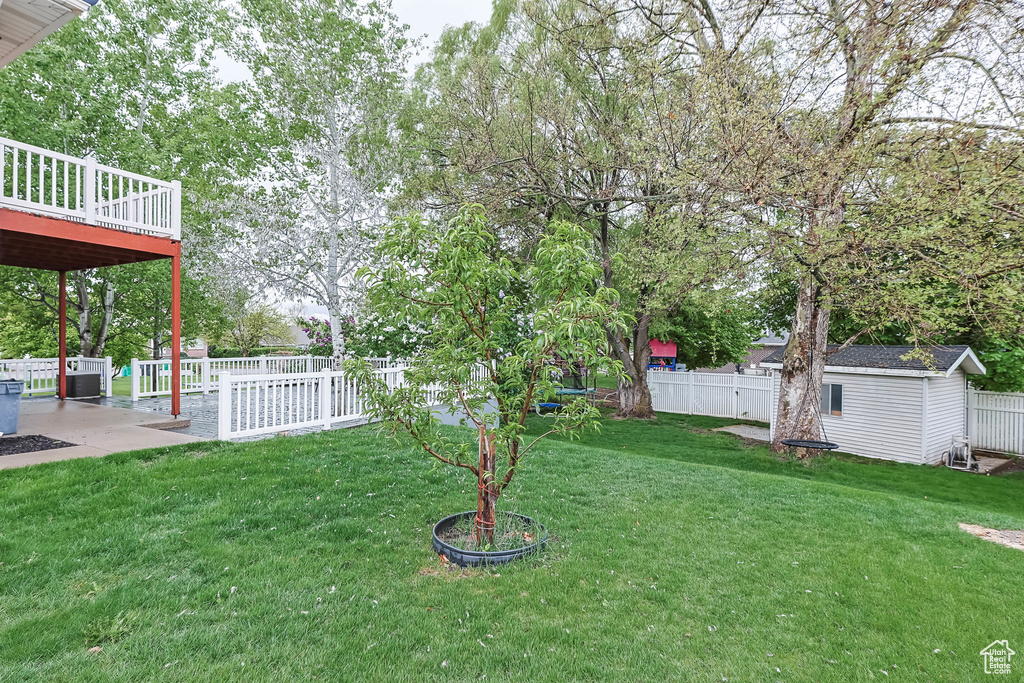 View of yard featuring a fenced backyard, a storage unit, an outbuilding, and a wooden deck