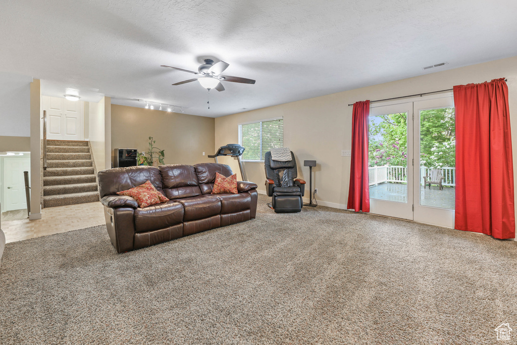 Living area featuring stairs, a ceiling fan, rail lighting, and carpet flooring
