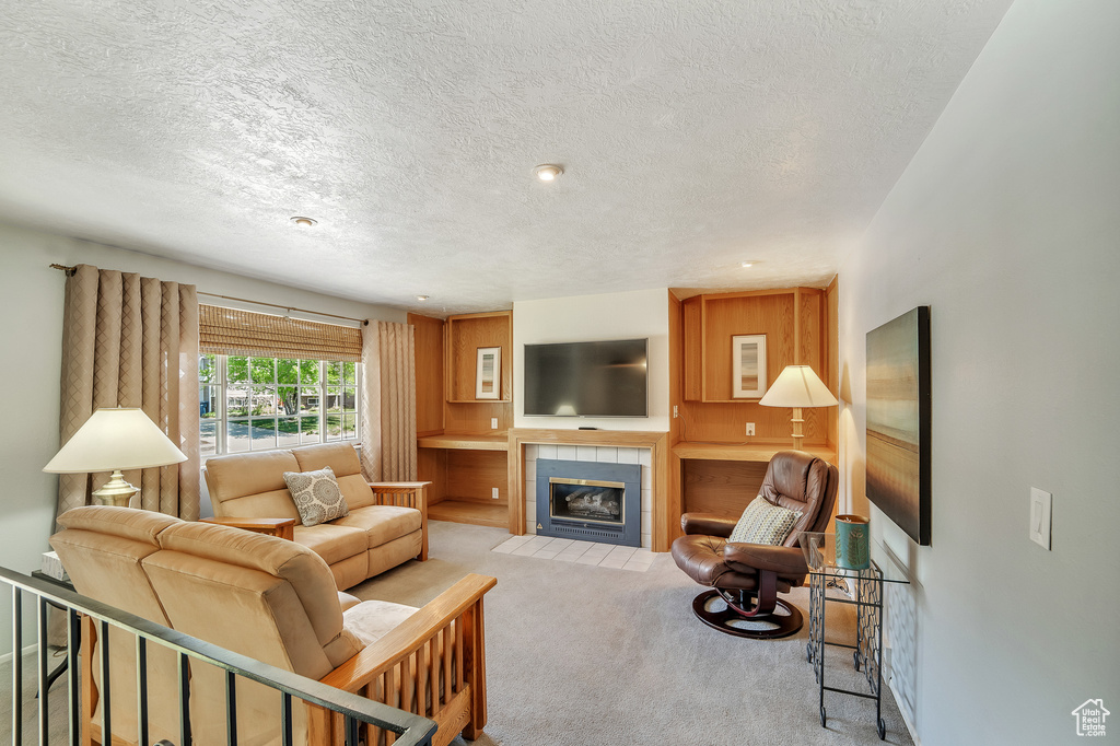 Living room featuring carpet, a textured ceiling, and a tile fireplace