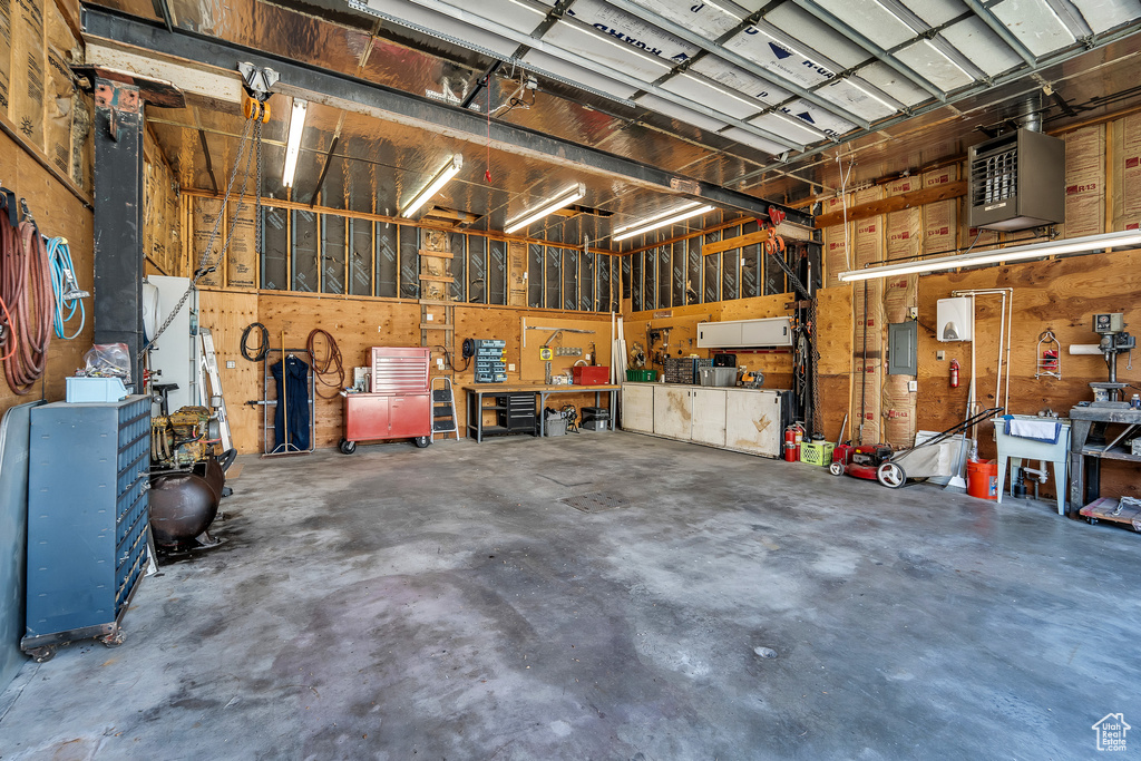 Garage featuring a heating unit, electric panel, and a workshop area