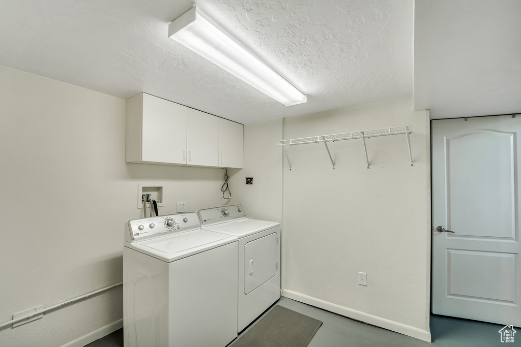 Laundry room featuring cabinet space, a textured ceiling, baseboards, and washer and dryer
