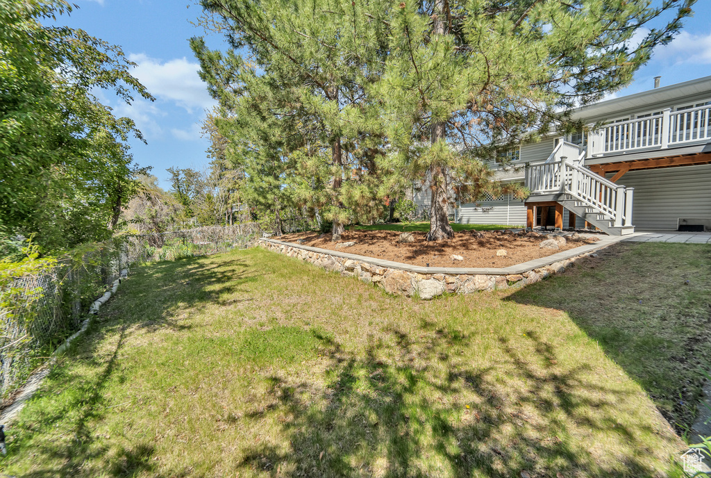 View of yard with stairs, a wooden deck, and fence