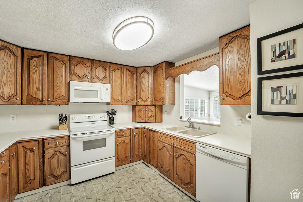 Kitchen featuring brown cabinets and white appliances