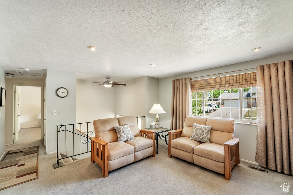 Living area with carpet floors, visible vents, recessed lighting, a textured ceiling, and a ceiling fan