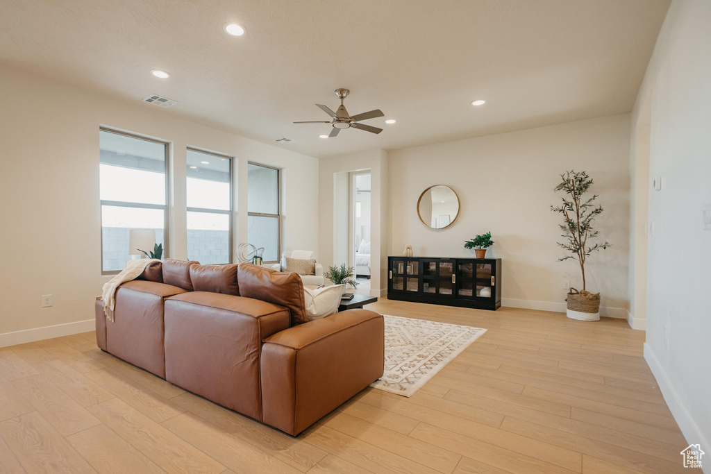 Living area featuring a ceiling fan, baseboards, recessed lighting, and light wood-type flooring