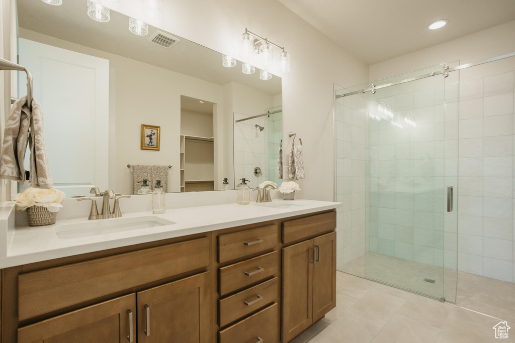 Bathroom featuring double vanity, visible vents, a shower stall, and a sink