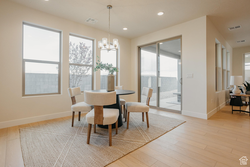 Dining room featuring visible vents, baseboards, light wood finished floors, and a notable chandelier