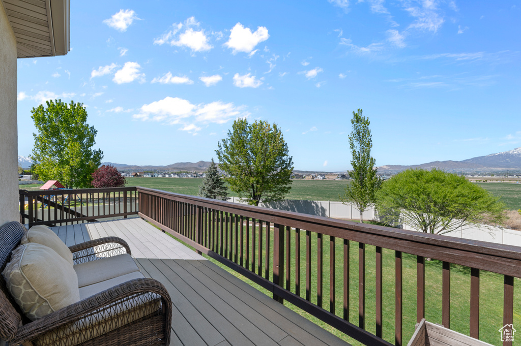 Wooden deck featuring a lawn, a mountain view, and fence