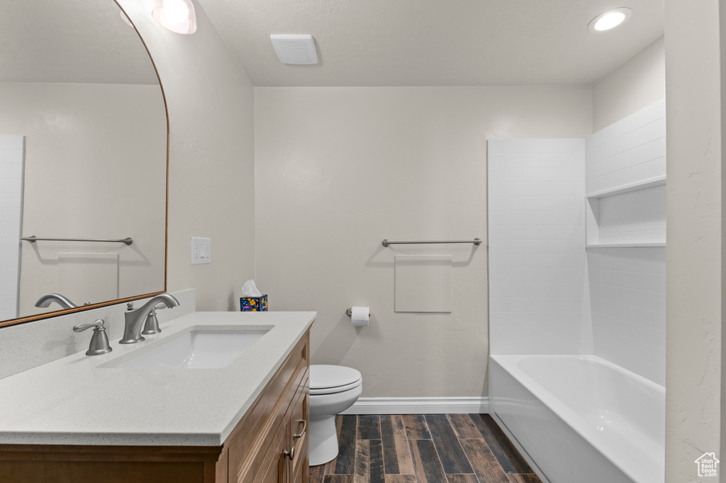 Full bath with baseboards, vanity, toilet, and wood finished floors