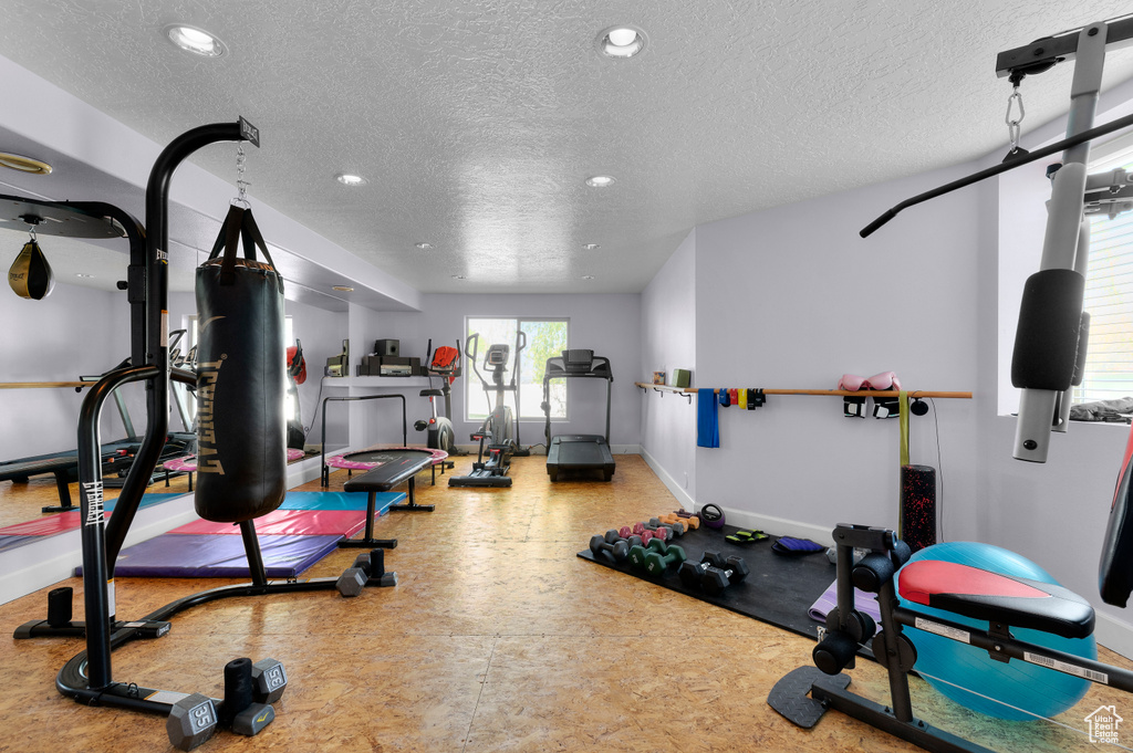 Exercise area with recessed lighting, a textured ceiling, and baseboards