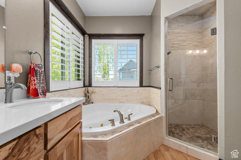 Full bathroom featuring a jetted tub, wood finished floors, vanity, and a shower stall