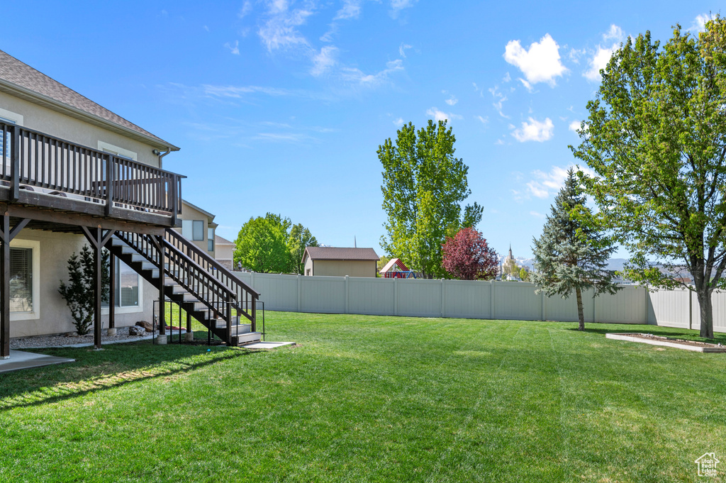 View of yard with a fenced backyard, a wooden deck, and stairway