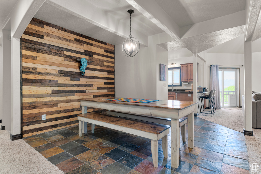 Dining space featuring stone tile floors, a notable chandelier, and wooden walls