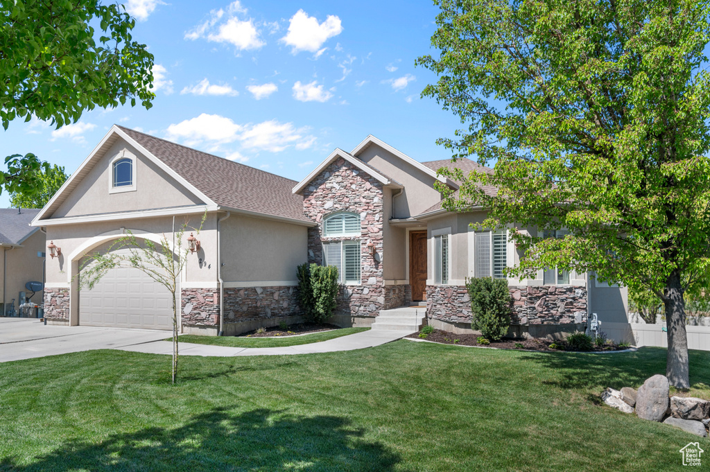 Craftsman-style house featuring stone siding, a garage, stucco siding, a front yard, and driveway