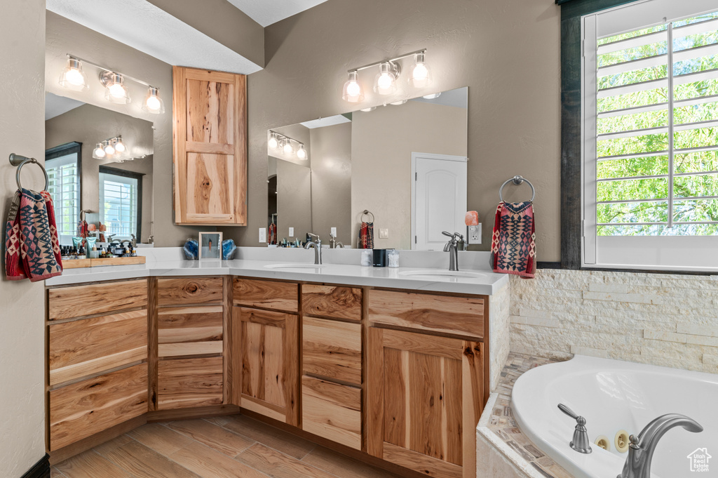 Full bath featuring a healthy amount of sunlight, vanity, and a whirlpool tub