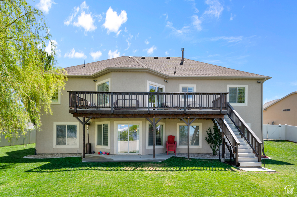 Rear view of house with stucco siding, a deck, a fenced backyard, a patio area, and a lawn