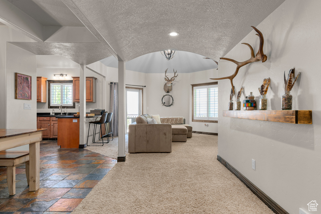 Living area with a textured ceiling, baseboards, lofted ceiling, recessed lighting, and stone tile floors