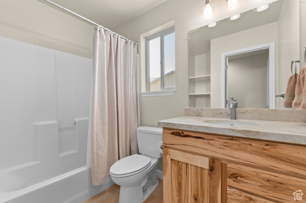 Full bath featuring vanity, shower / bath combo, toilet, and wood finished floors