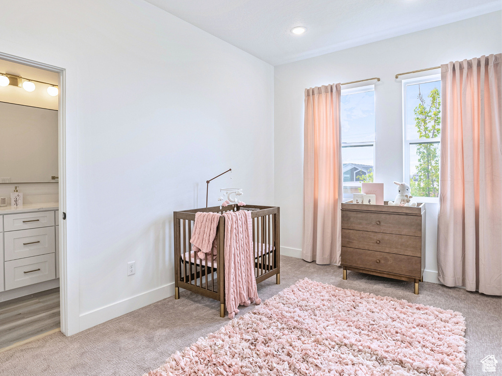 Bedroom featuring a nursery area, baseboards, recessed lighting, and light colored carpet