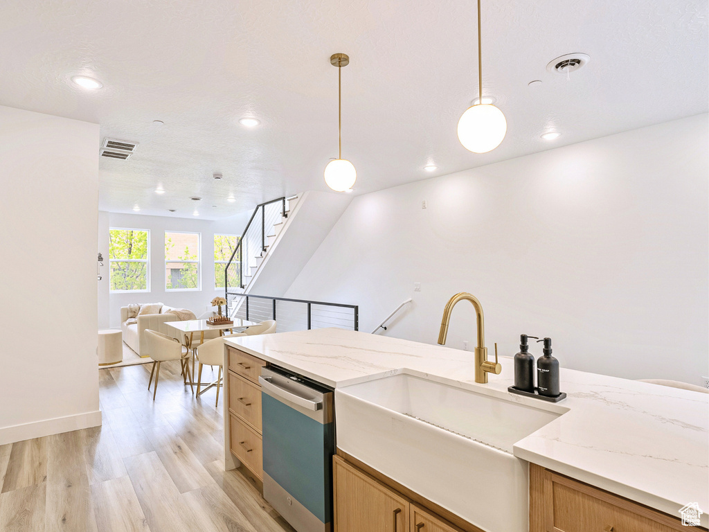 Kitchen with a sink, dishwasher, light wood-style flooring, open floor plan, and visible vents