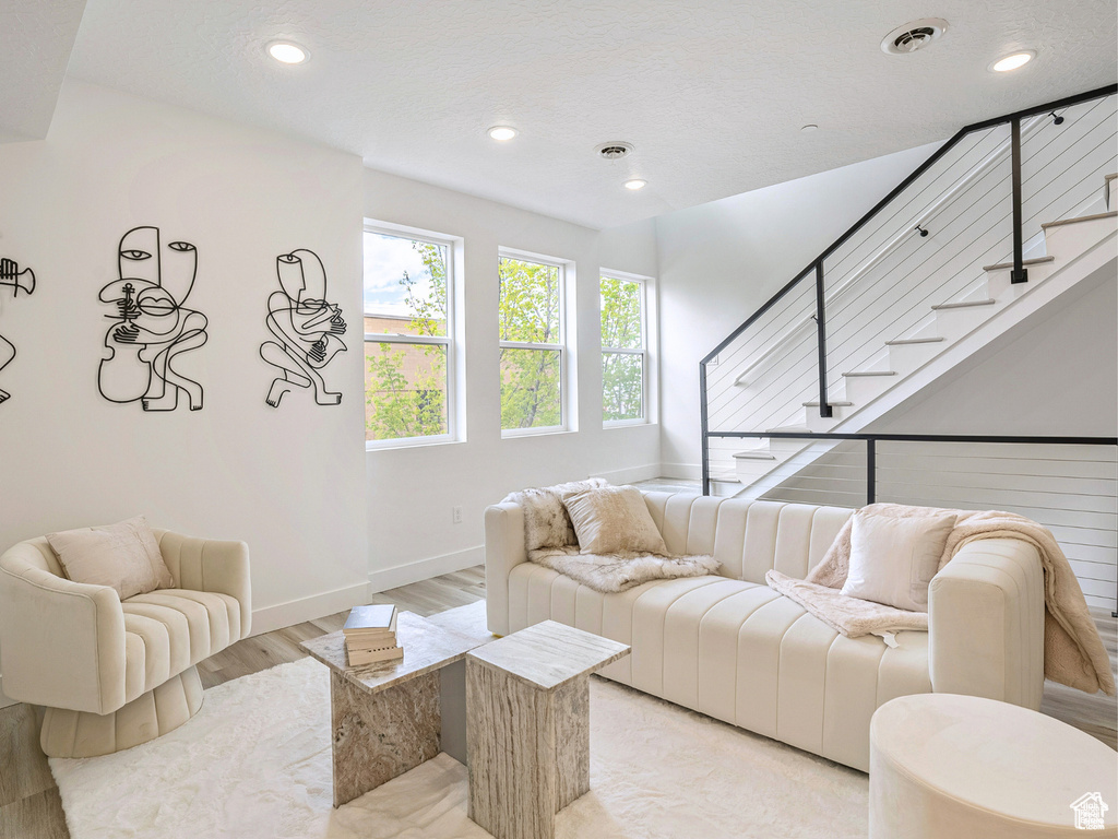 Living room featuring visible vents, baseboards, stairway, recessed lighting, and light wood-type flooring