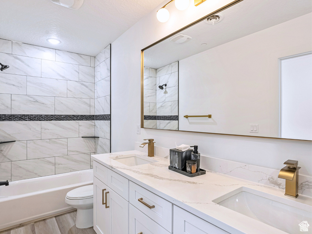 Full bath featuring shower / tub combination, a sink, a textured ceiling, and toilet