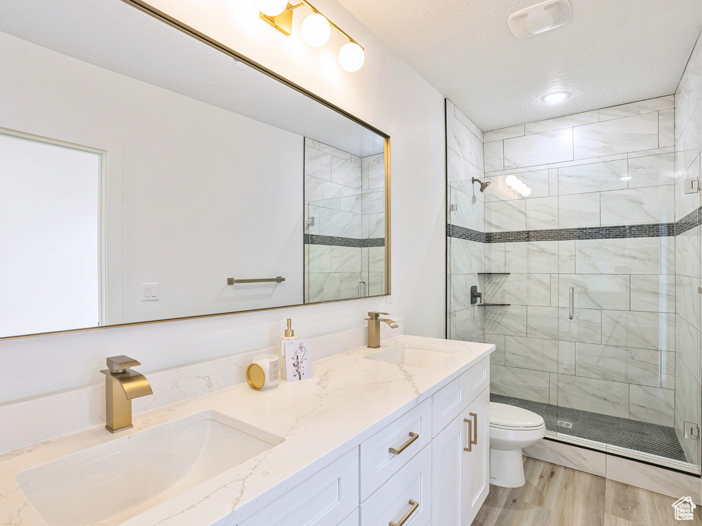 Bathroom featuring double vanity, a sink, toilet, and a shower stall