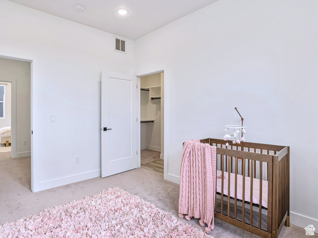 Bedroom featuring baseboards, a walk in closet, carpet flooring, and visible vents