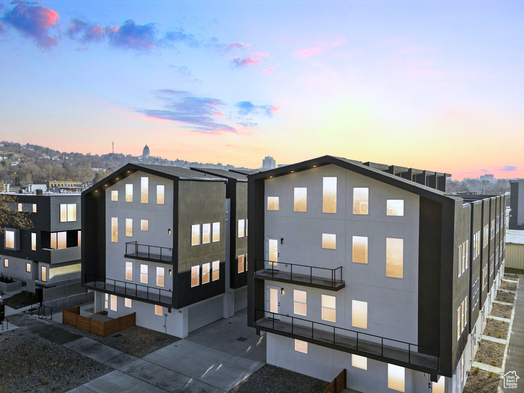 Back of house at dusk with a balcony and stucco siding