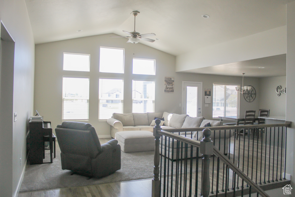 Living room with baseboards, ceiling fan with notable chandelier, wood finished floors, and lofted ceiling