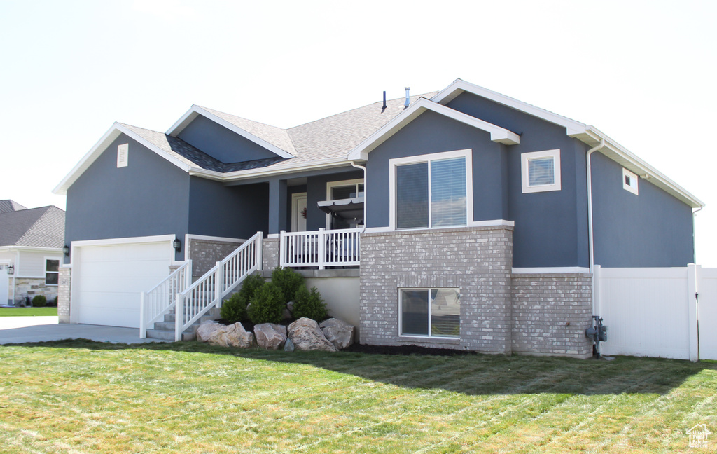 View of front of home featuring fence, brick siding, a front yard, concrete driveway, and covered porch