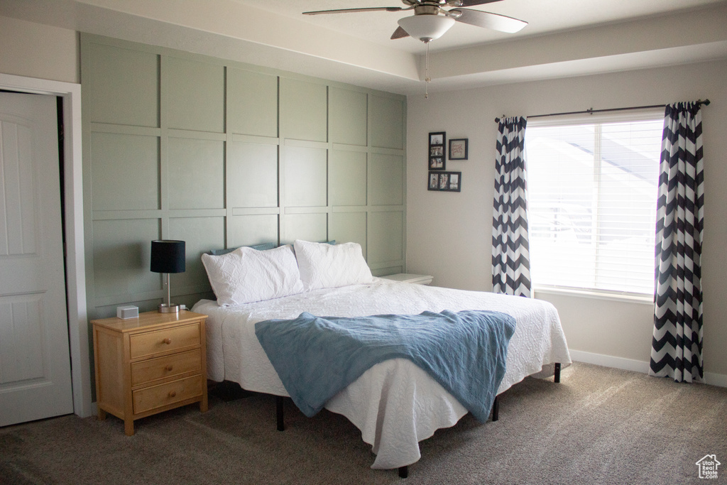 Bedroom featuring baseboards, carpet flooring, a ceiling fan, and multiple windows