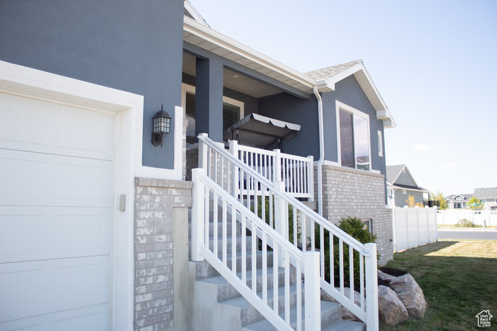 View of exterior entry featuring a garage, covered porch, stucco siding, and brick siding