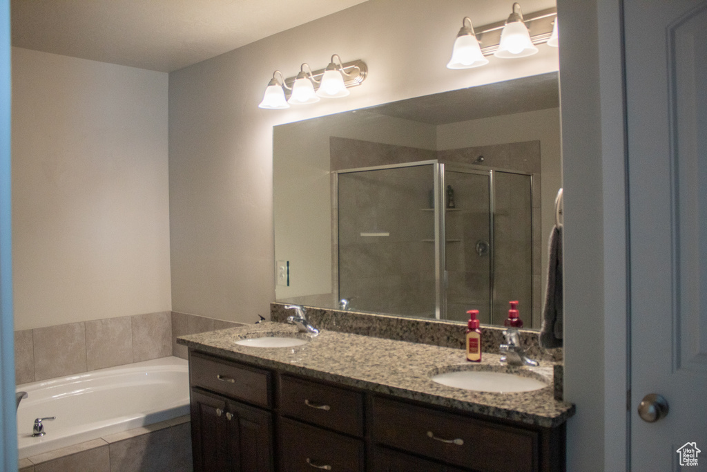 Bathroom featuring double vanity, a sink, a garden tub, and a stall shower