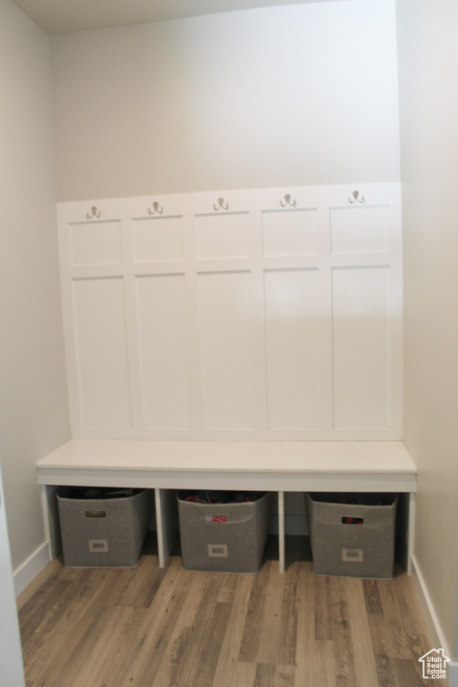 Mudroom with built in study area, baseboards, and light wood finished floors