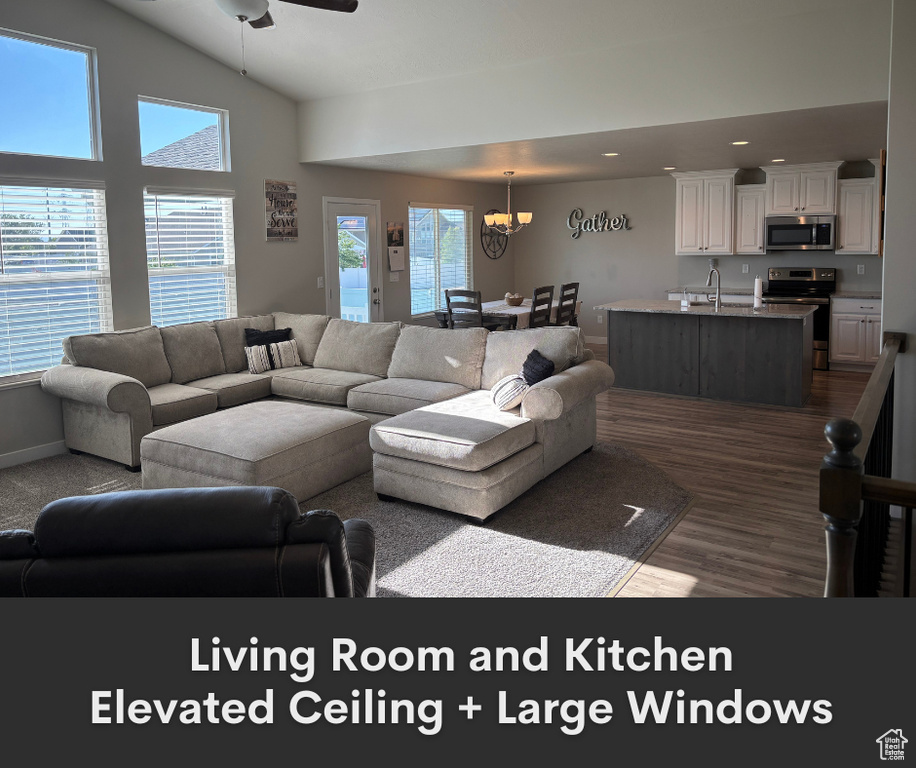 Living room featuring a chandelier, dark wood-type flooring, ceiling fan, recessed lighting, and baseboards