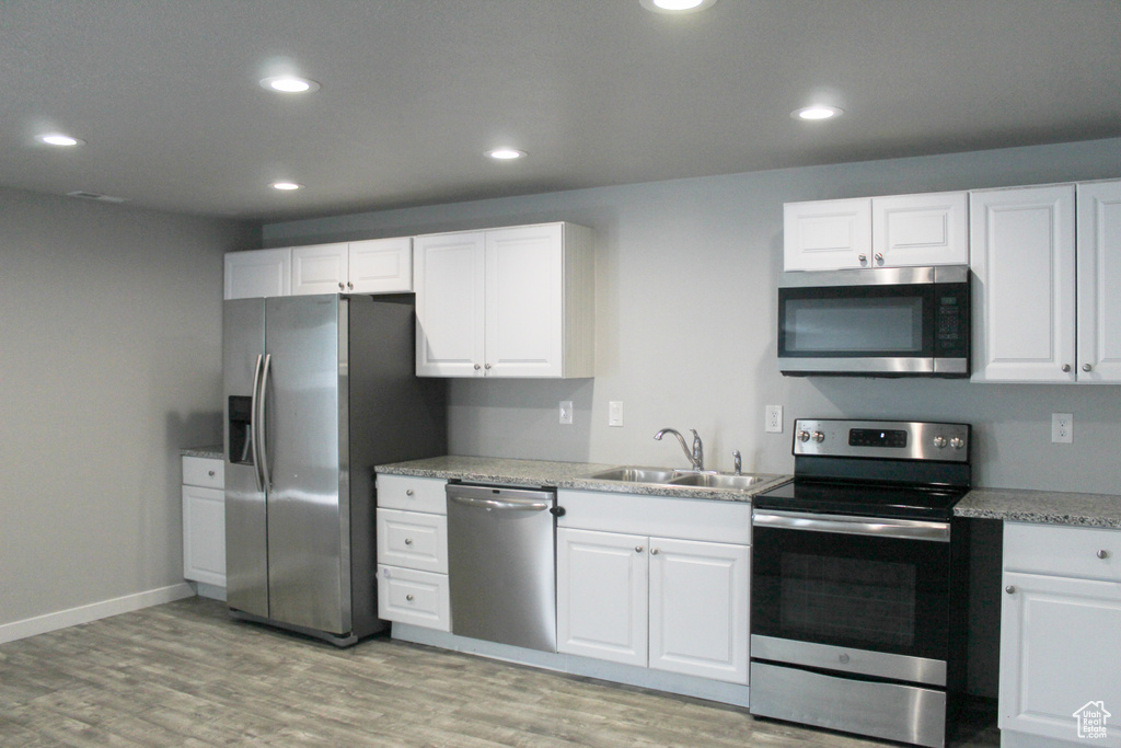 Kitchen featuring recessed lighting, white cabinetry, a sink, light wood-style flooring, and stainless steel appliances