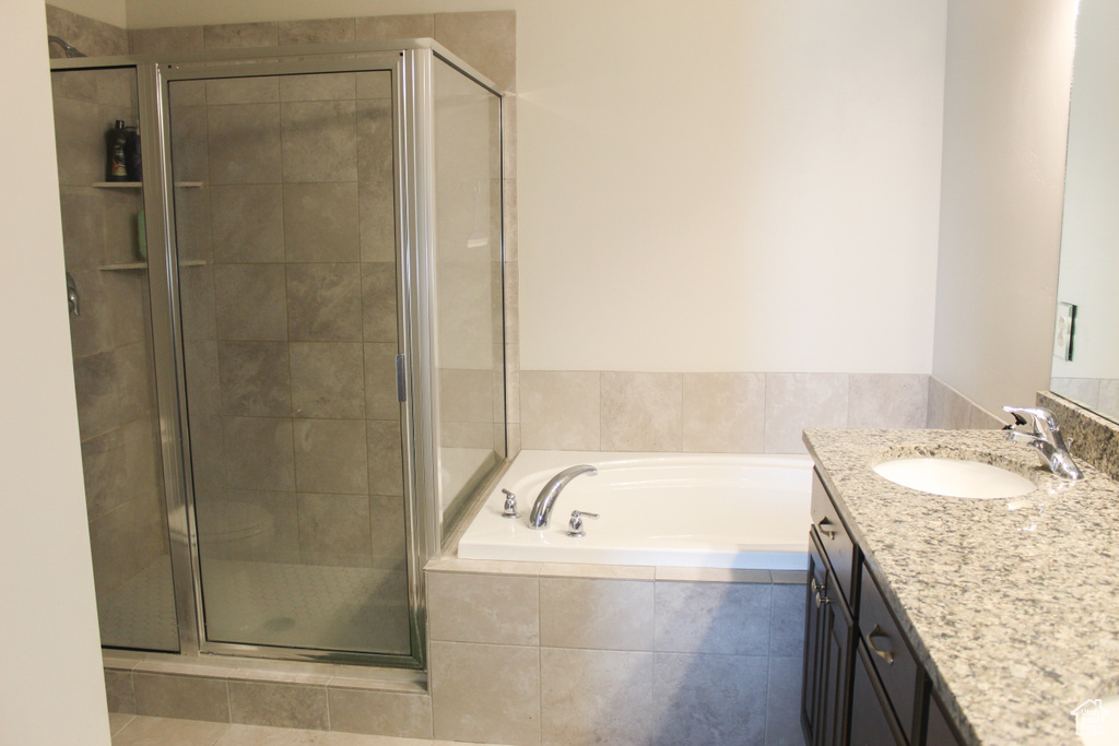 Bathroom featuring a shower stall, a bath, and vanity