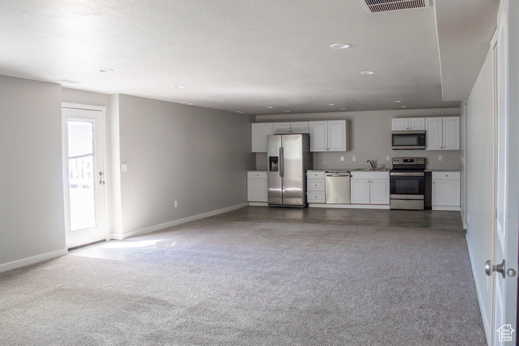 Unfurnished living room with a sink, carpet floors, recessed lighting, baseboards, and visible vents