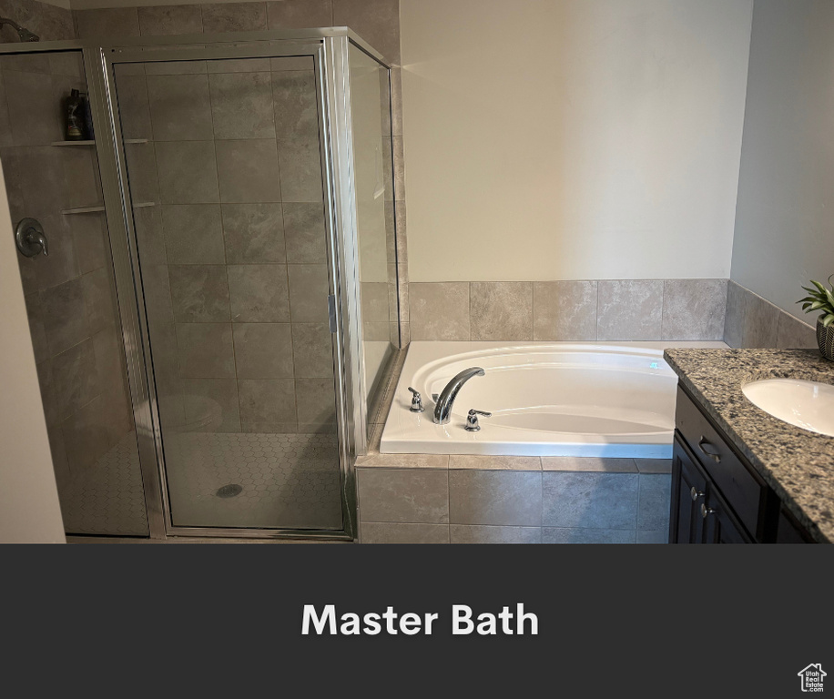 Bathroom featuring a garden tub, a stall shower, and vanity