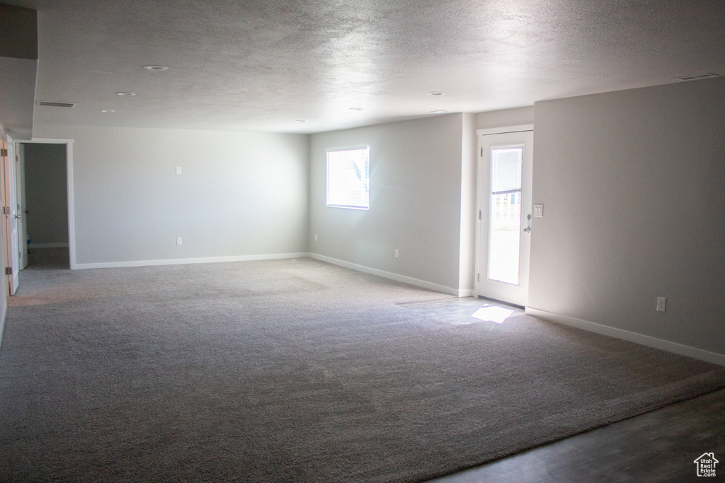 Unfurnished room with baseboards, a textured ceiling, and carpet floors