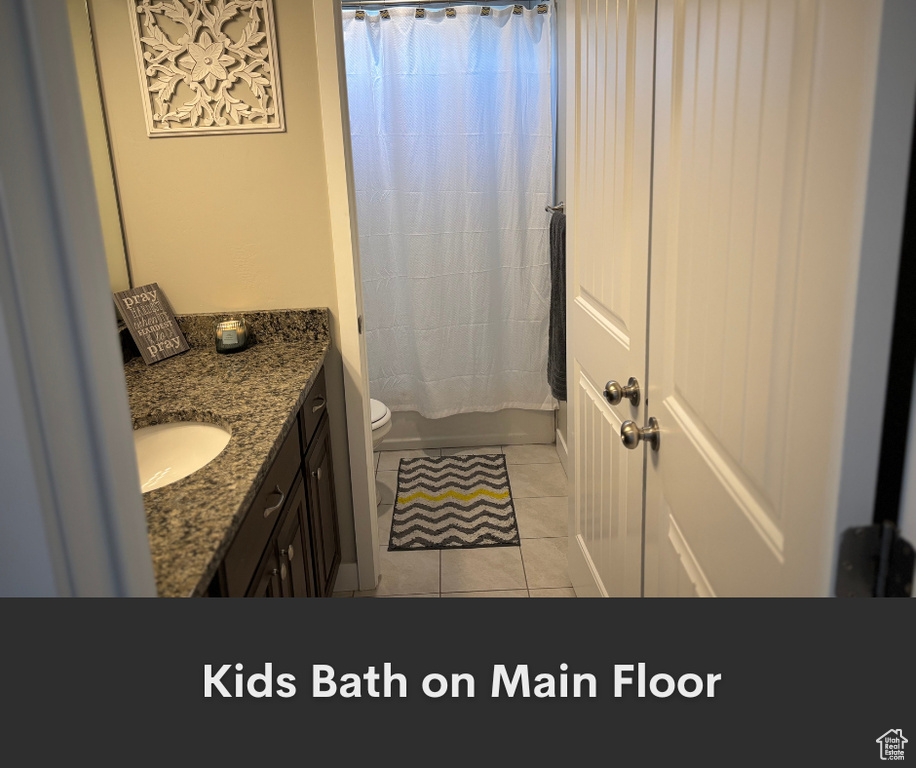 Bathroom with vanity, toilet, tile patterned flooring, and shower / bath combination with curtain