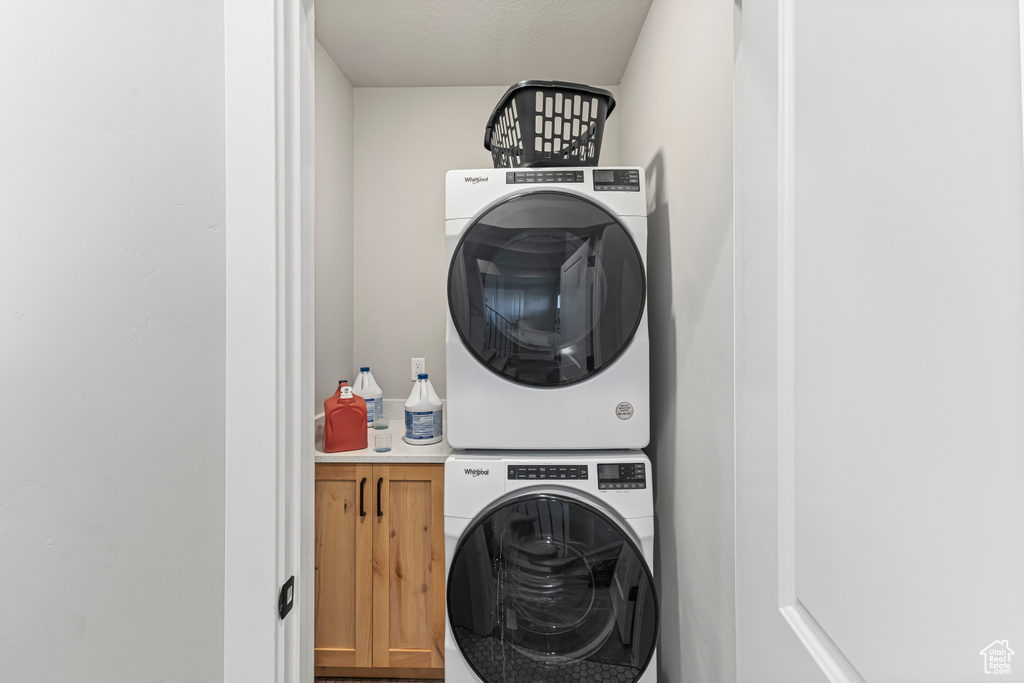 Laundry area featuring cabinet space and stacked washer and clothes dryer