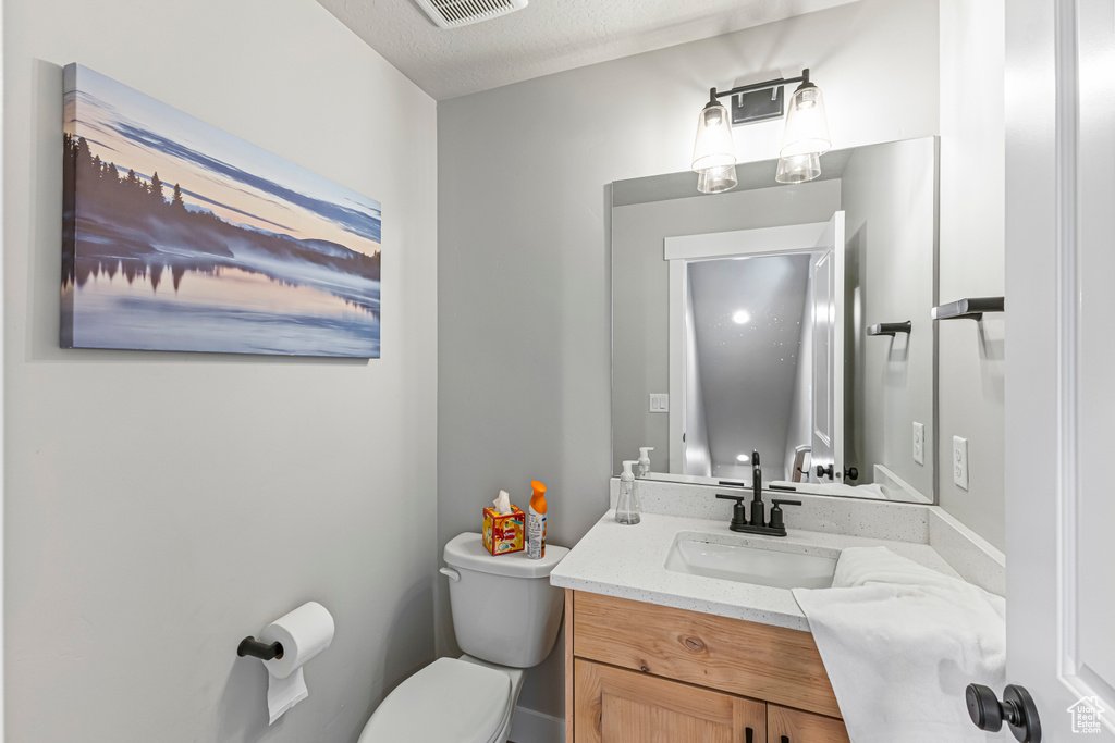 Half bathroom featuring toilet, visible vents, and vanity