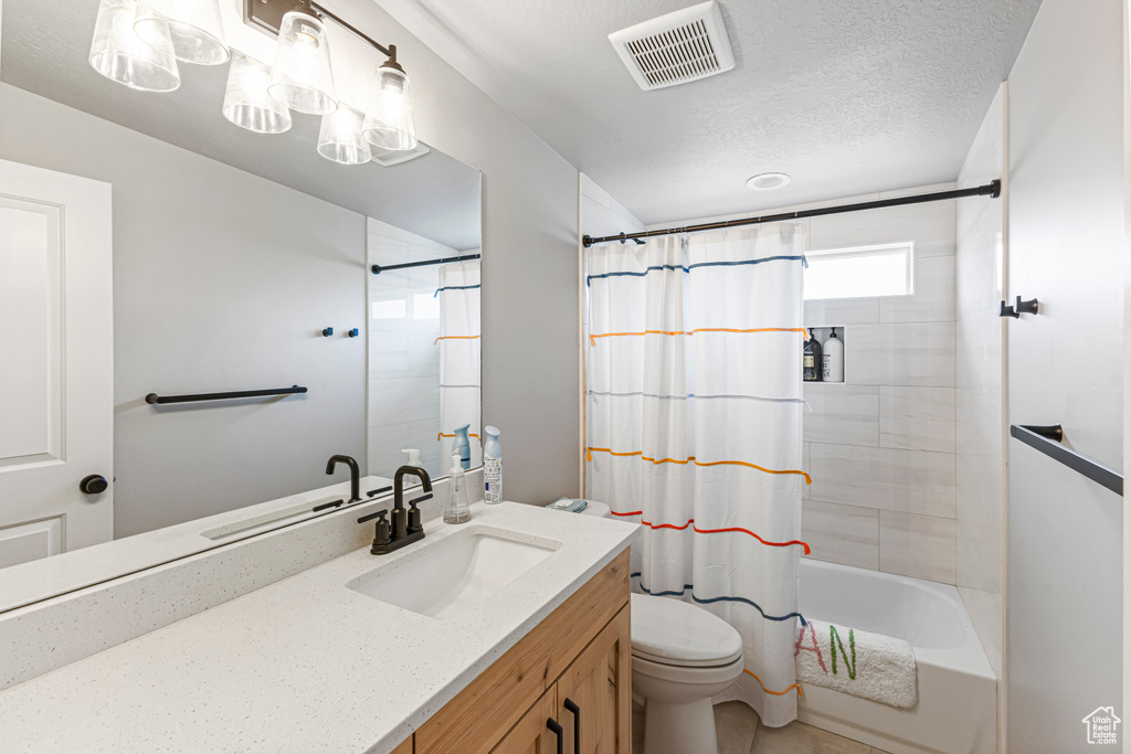 Full bathroom featuring a textured ceiling, visible vents, shower / tub combo, vanity, and toilet