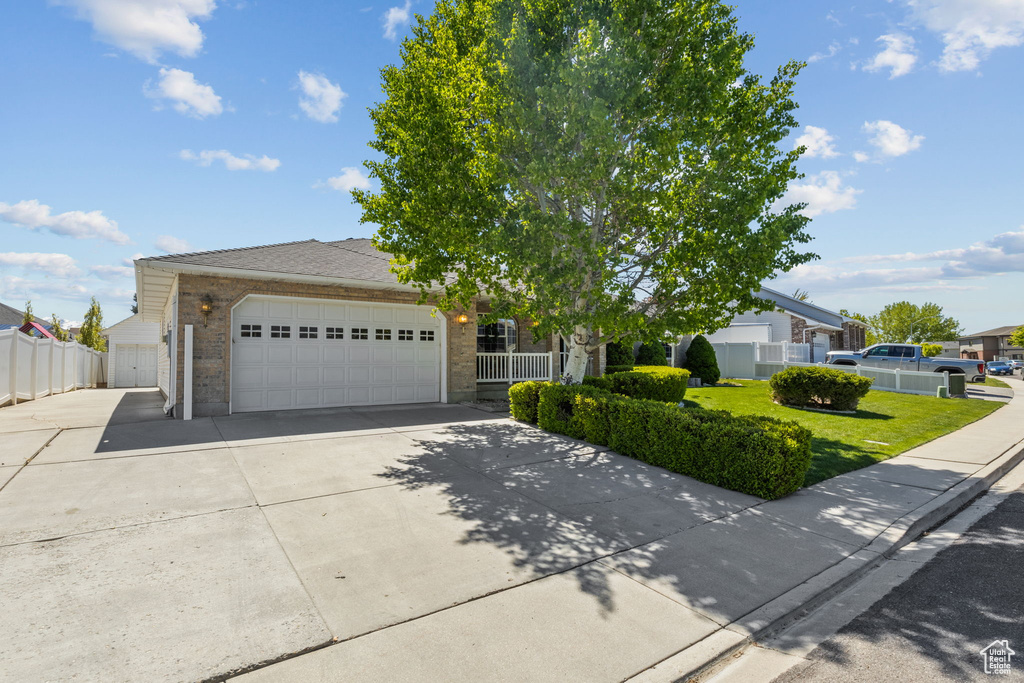 Obstructed view of property with fence, an attached garage, driveway, and brick siding